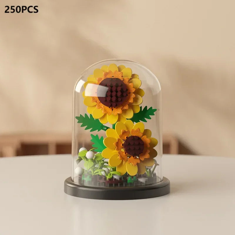 A clear glass enclosure displaying a miniature sunflower arrangement made of building blocks.