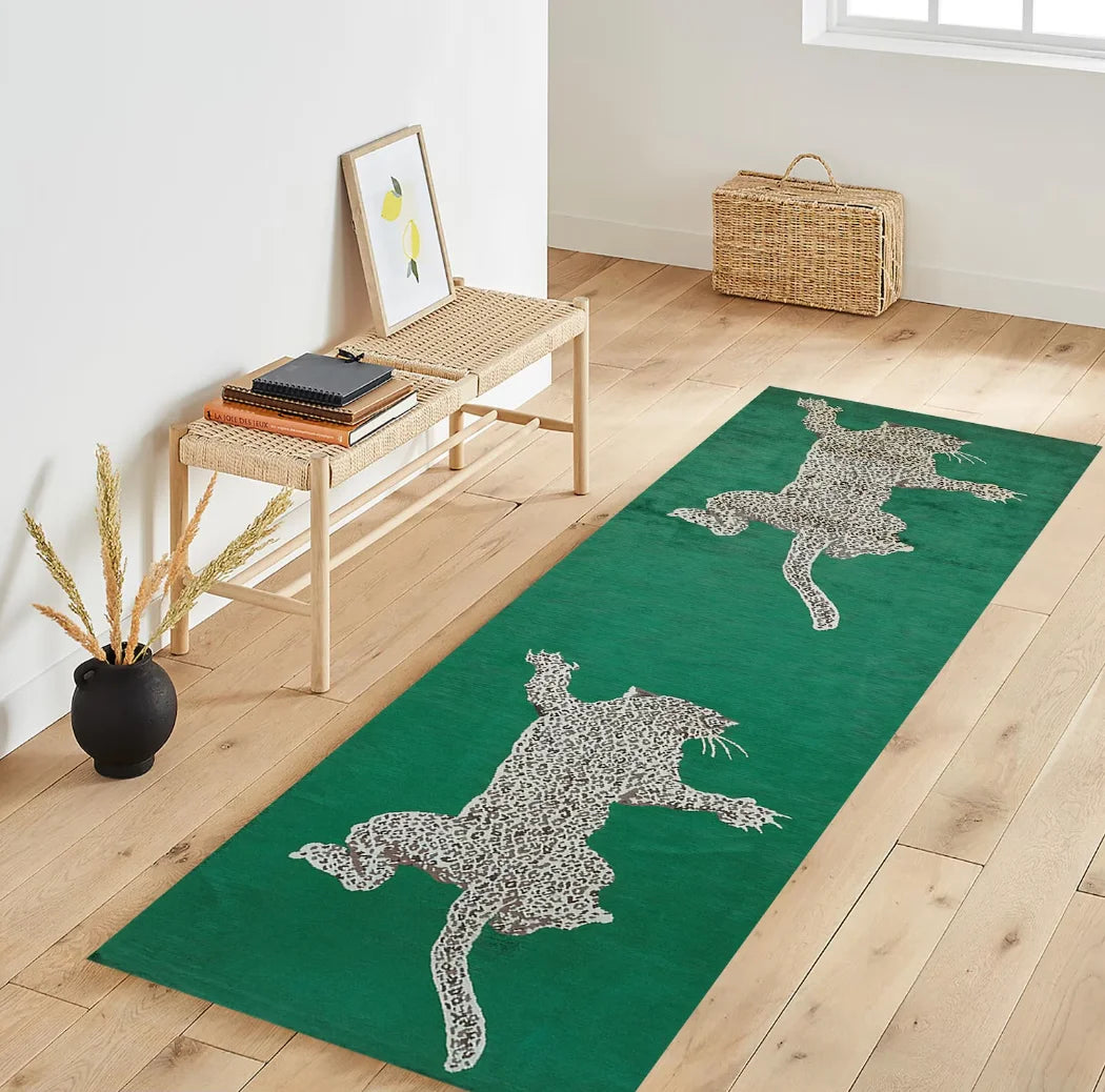 A green runner rug with a gray animal print design is displayed on a light wood floor.