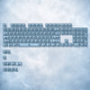 A collection of 115 keycaps in a light blue or clear color, arranged in a rectangular grid against a cloudy background.