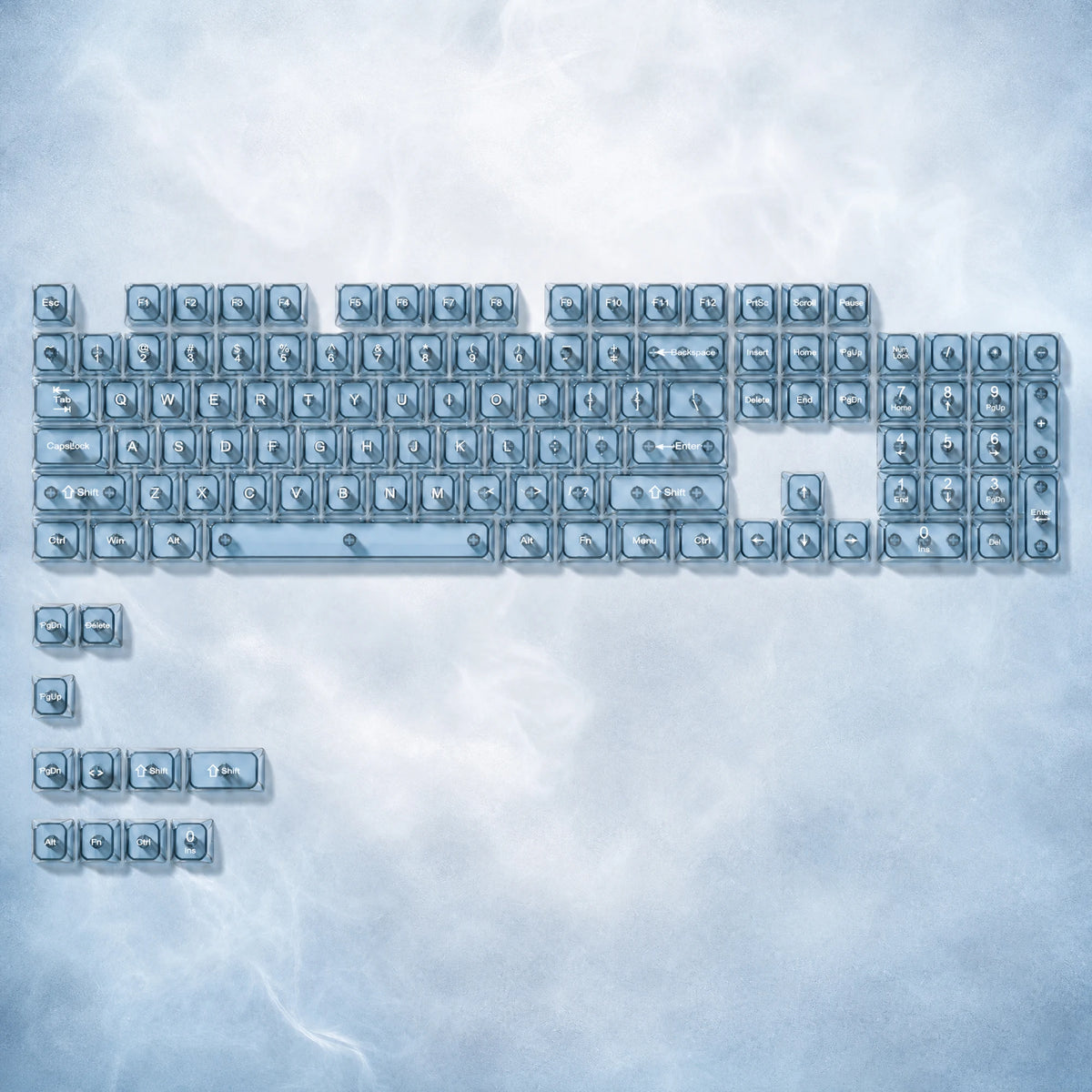 A collection of 115 keycaps in a light blue or clear color, arranged in a rectangular grid against a cloudy background.