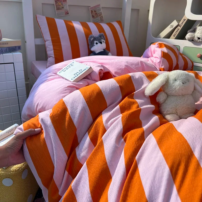 An orange and pink striped duvet cover set with matching pillowcases is displayed on a bed.