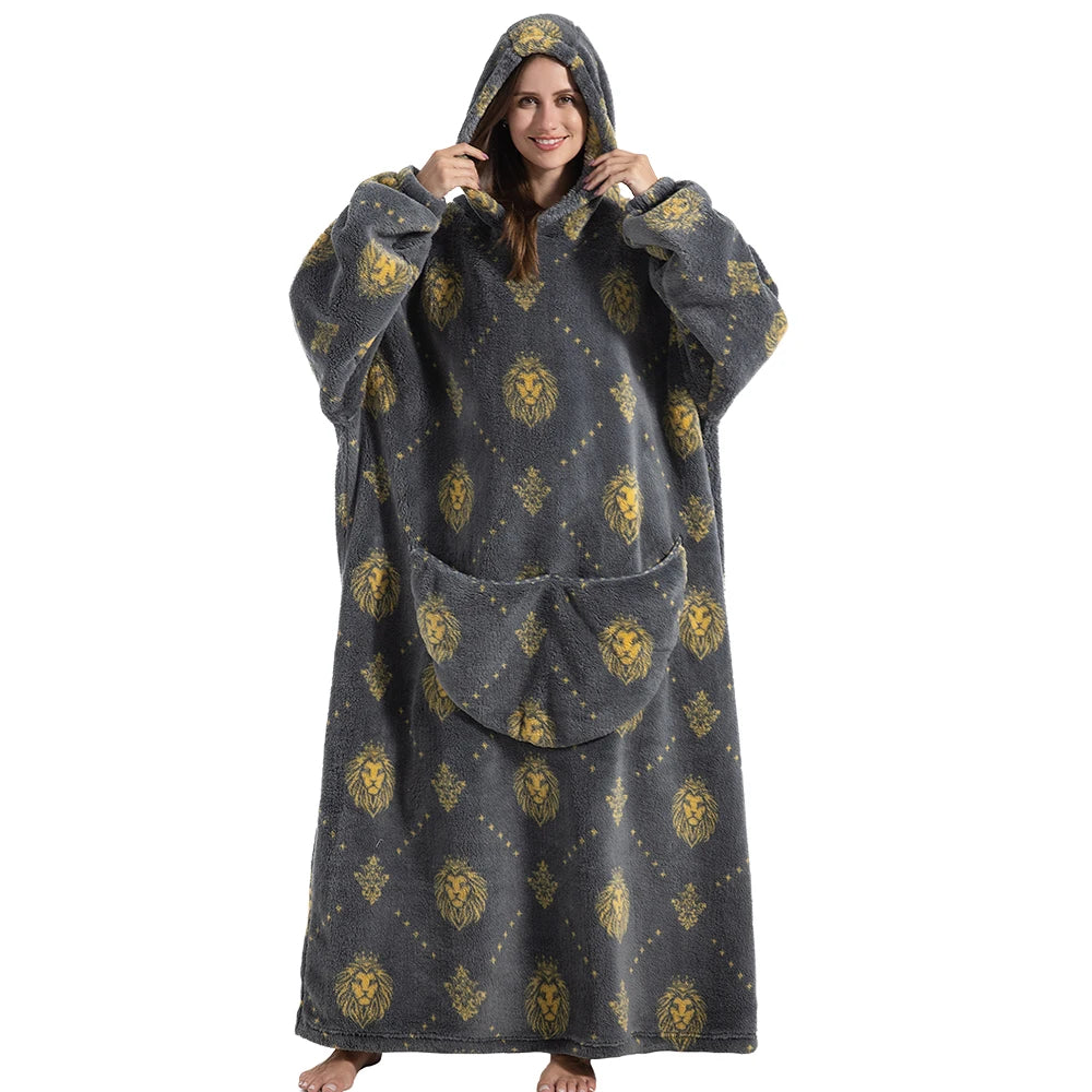 A woman wearing an oversized gray wearable blanket hoodie with a hood and sleeves, featuring a gold lion pattern.
