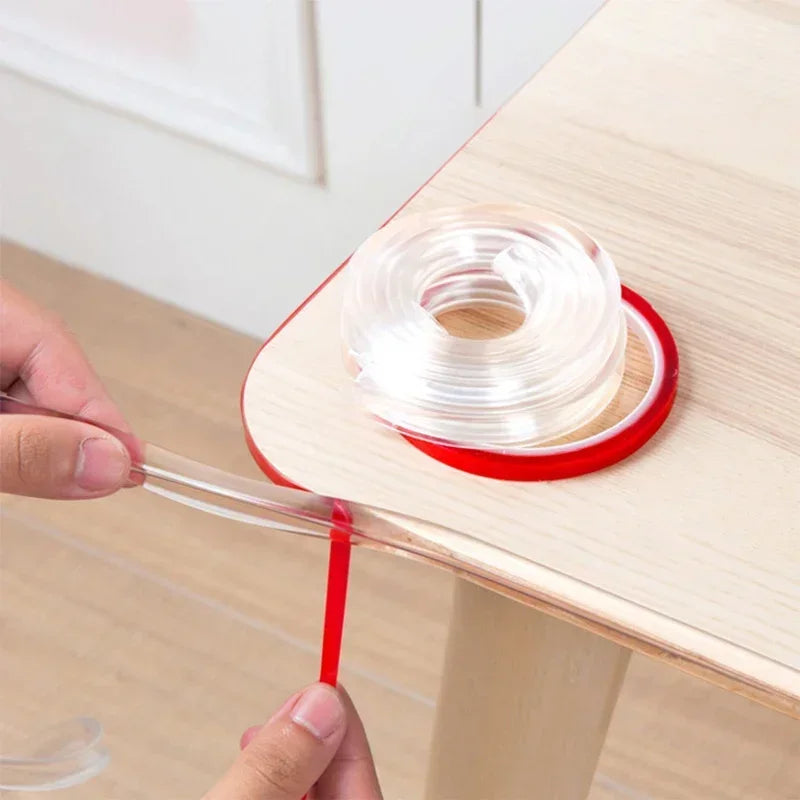 Hands are installing transparent silicone corner guards onto a wooden table edge for baby safety.