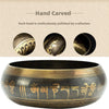 A hand-carved brass Tibetan singing bowl with intricate engravings and a dark finish.
