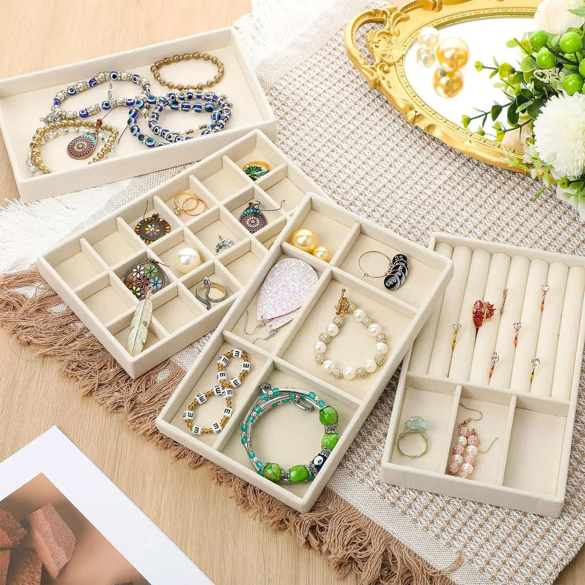 A light wood velvet jewelry organizer tray with detachable compartments holding various gold and silver jewelry pieces.