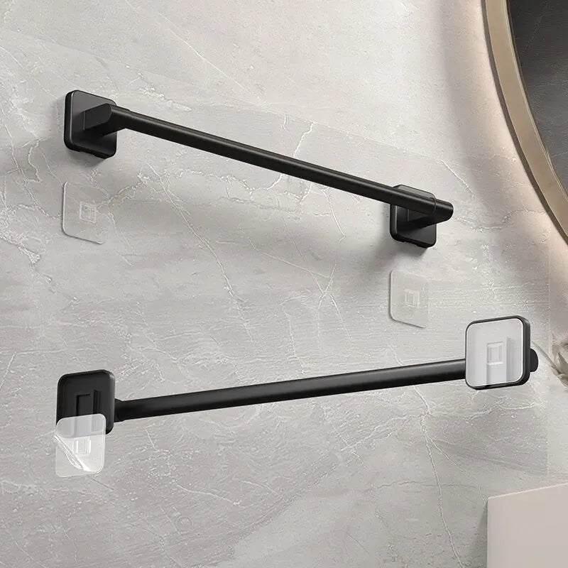 A black wall-mounted towel rack with adhesive mounting hardware installed on a light gray wall.