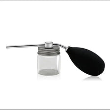 A silver and black refillable spray bottle with a long applicator for precision styling.