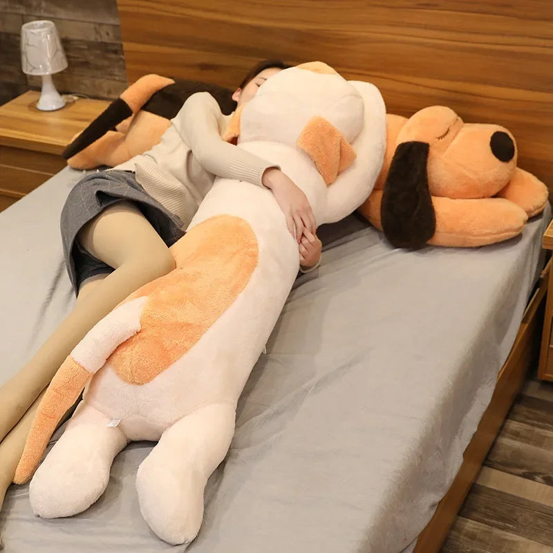 A large, light-colored dog plush pillow is lying on a table covered with a gray cloth.