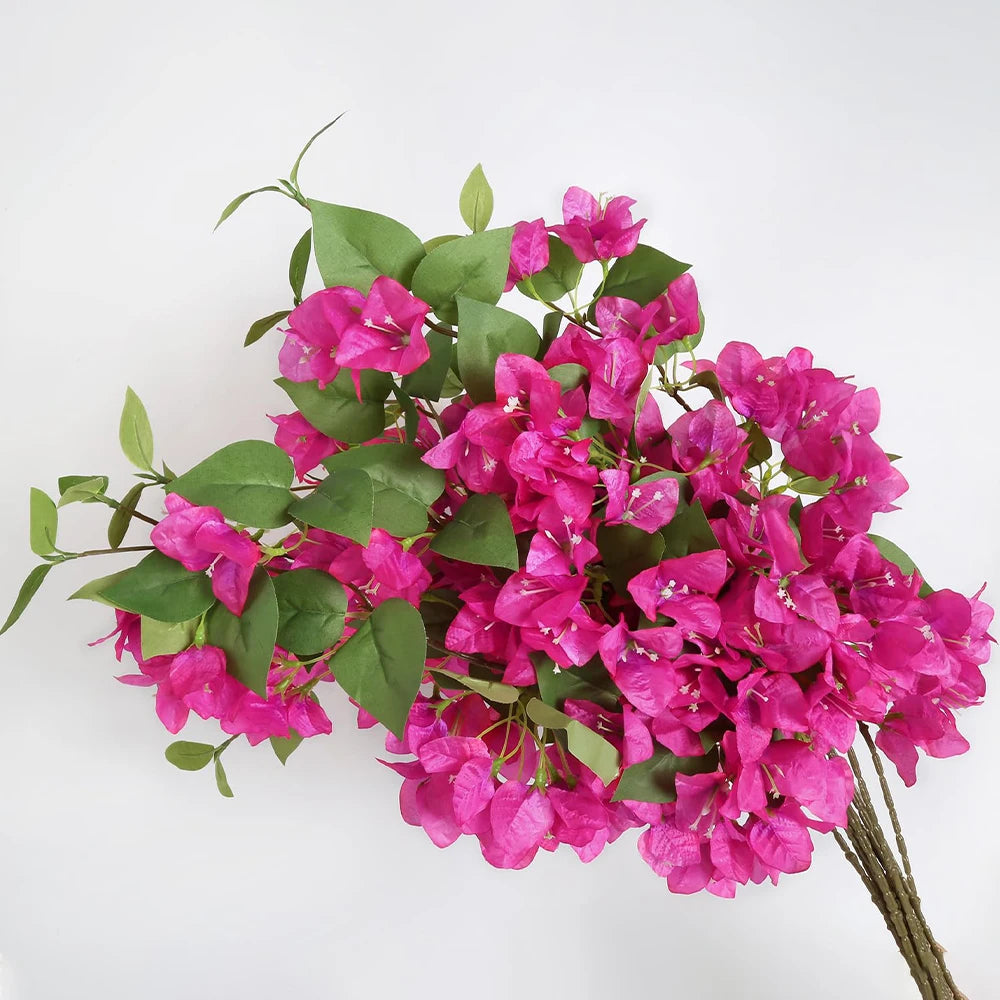 A cluster of vibrant magenta artificial bougainvillea vine branches with green leaves.