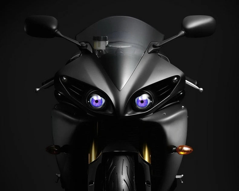Close-up of a black motorcycle headlight featuring a striking purple LED eye design.