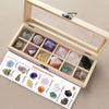 A wooden gift box containing twelve natural gemstone crystals arranged in compartments.
