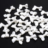 A pile of 100 white acrylic pearl spacer beads shaped like bows for jewelry making