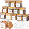 A collection of five square glass spice jars with bamboo lids and labels, including white pepper, bay leaves, sesame seed, le
