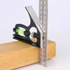 A black and silver adjustable combination square with a spirit level is shown resting on a wooden surface next to a ruler.