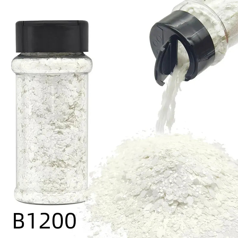 A glass jar of B1200 nail glitter mix with a black shaker top next to a pile of white glitter.