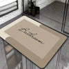 A rectangular beige bath mat with the word Bathroom written on it, displayed on a glass surface.