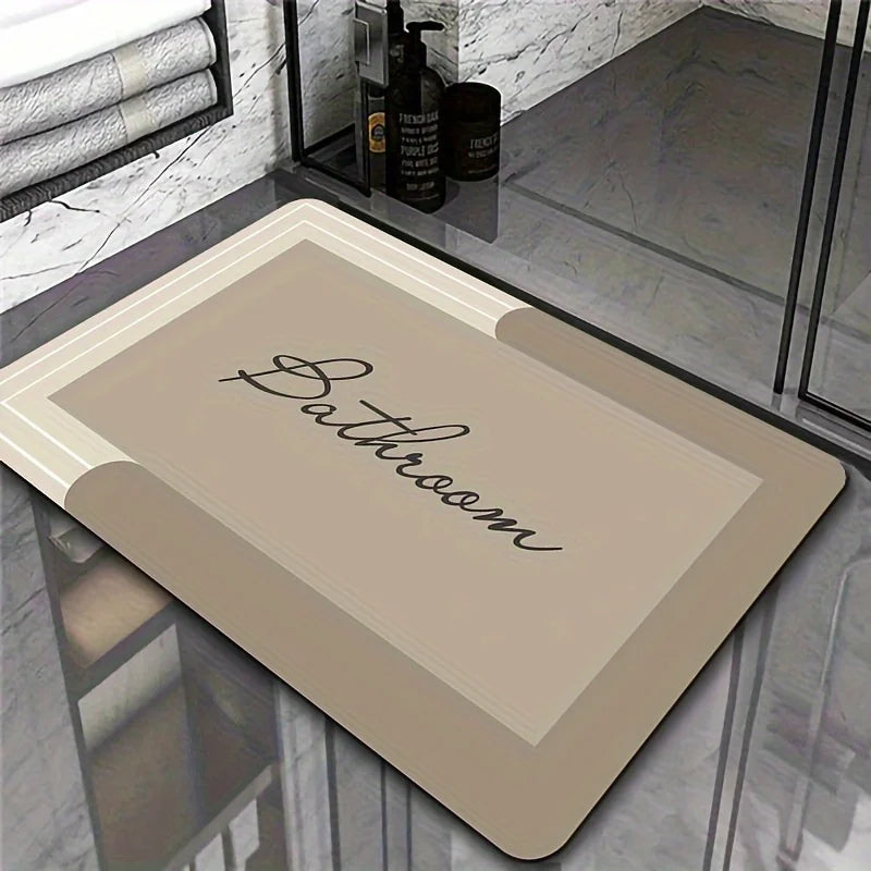 A rectangular beige bath mat with the word Bathroom written on it, displayed on a glass surface.