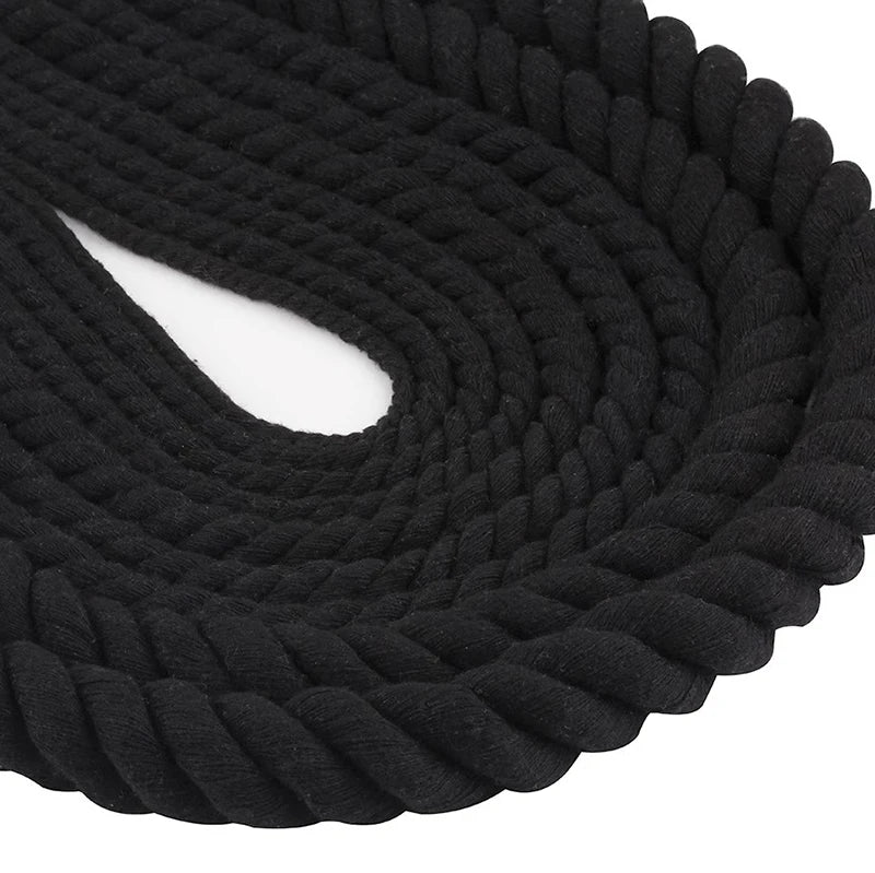 A close-up of black natural twisted cotton cord coiled into a thick rope.