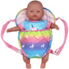 A baby doll is placed inside a pink and multicolored fabric carrier backpack with adjustable straps.