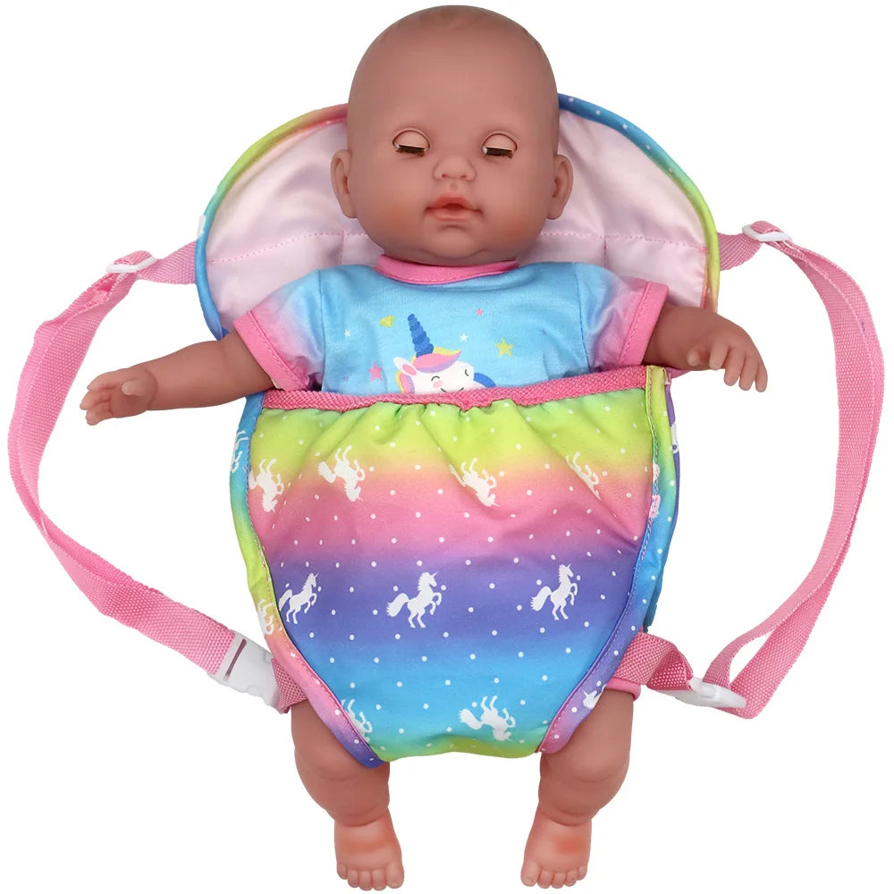 A baby doll is placed inside a pink and multicolored fabric carrier backpack with adjustable straps.