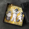 A set of handcrafted astronaut figurine resin spacemen desk decor displayed in a black box with glowing yellow filler.