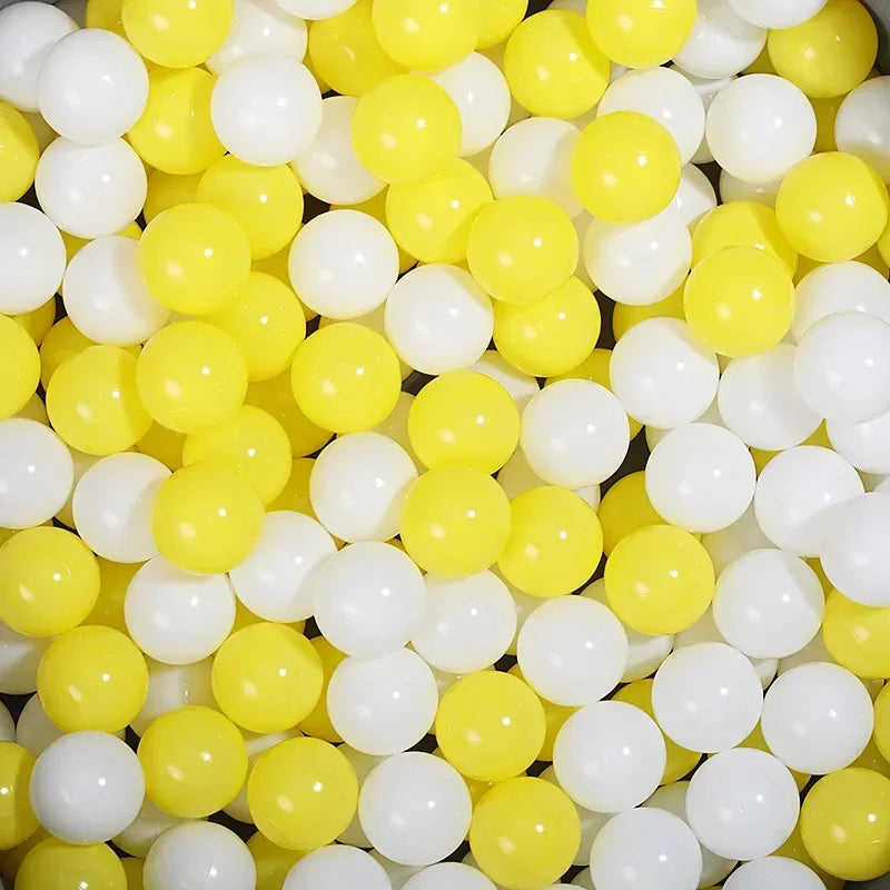 A close-up view of a large pack of colorful plastic balls in yellow and white for a ball pit.