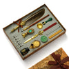 A wooden box contains a vintage calligraphy fountain pen set with various tools including a quill, ink, and wax seal stamp.