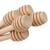 A close-up view of a natural wood honey dipper stick with ribbed ends.