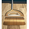 A golden broom and dustpan set with a floor wiper resting on a wooden floor.