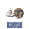 A round brass button with the text Jeans Jeans stamped on it, shown next to a silver button repair kit component.