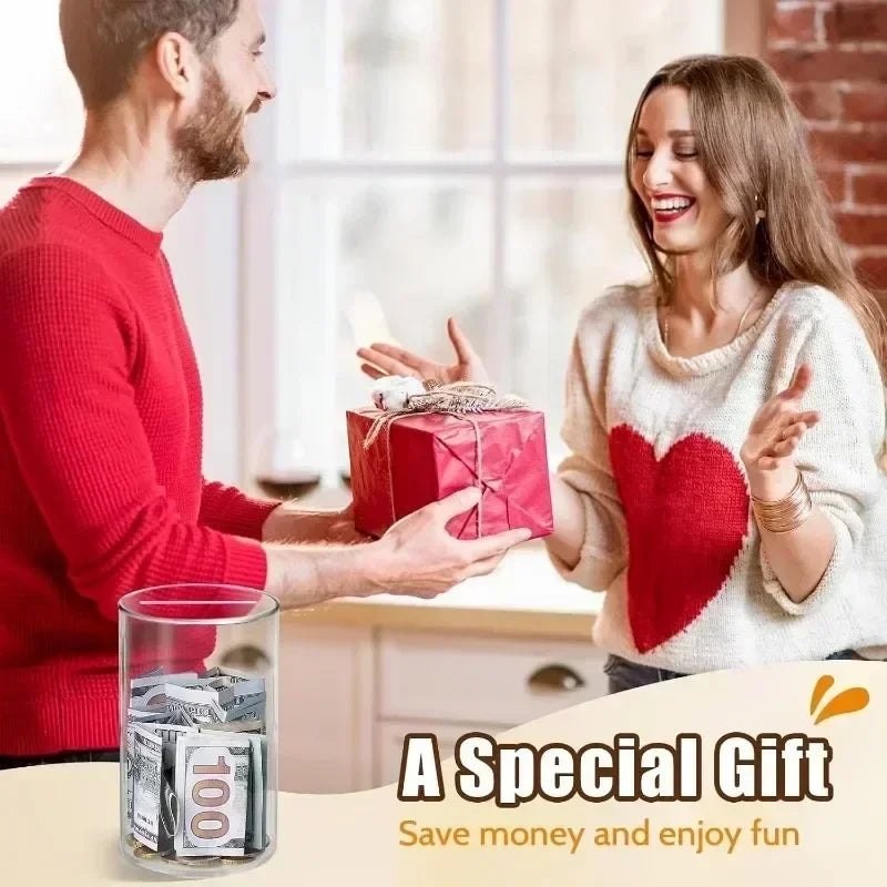 A man and a woman exchange a red gift box in a bright indoor setting with a clear acrylic piggy bank visible.