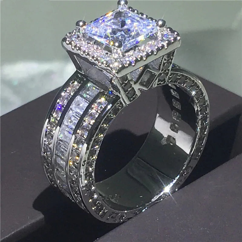 Bague ornementale argentée avec halo zircon, pierre centrale diamant brillant et accents pavés.