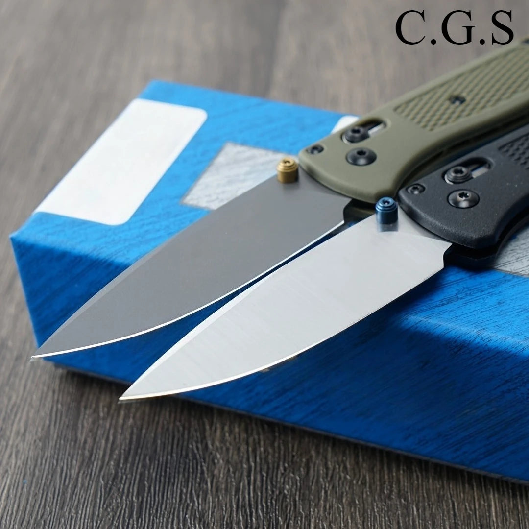 A folding knife with a drop point blade and a green handle is resting on a blue box.