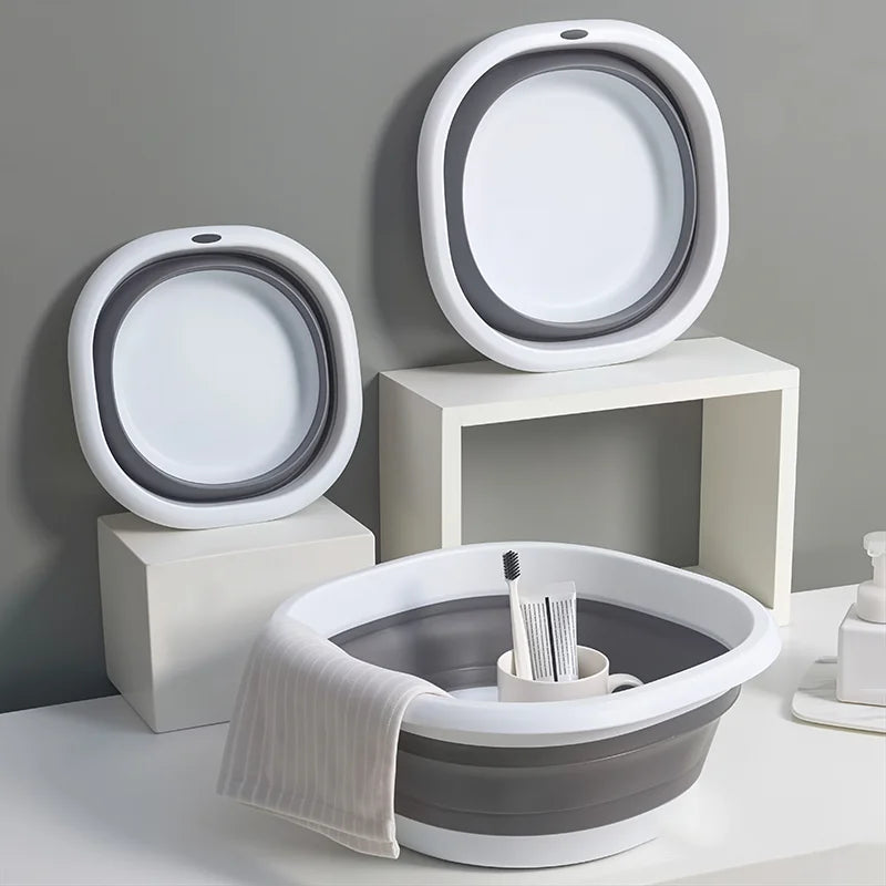 A set of white and gray collapsible silicone washbasins, including a large bowl and smaller basins, displayed on a white surf