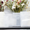 A set of clear plastic stamps and die for card making displayed in front of a floral arrangement.