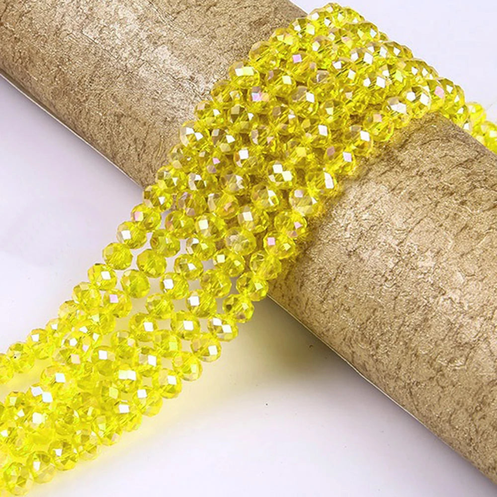 Yellow faceted crystal glass spacer beads threaded onto a cylindrical object.