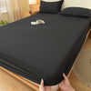 A dark gray fitted sheet is laid out on a bed, showing its smooth texture and elastic edge.