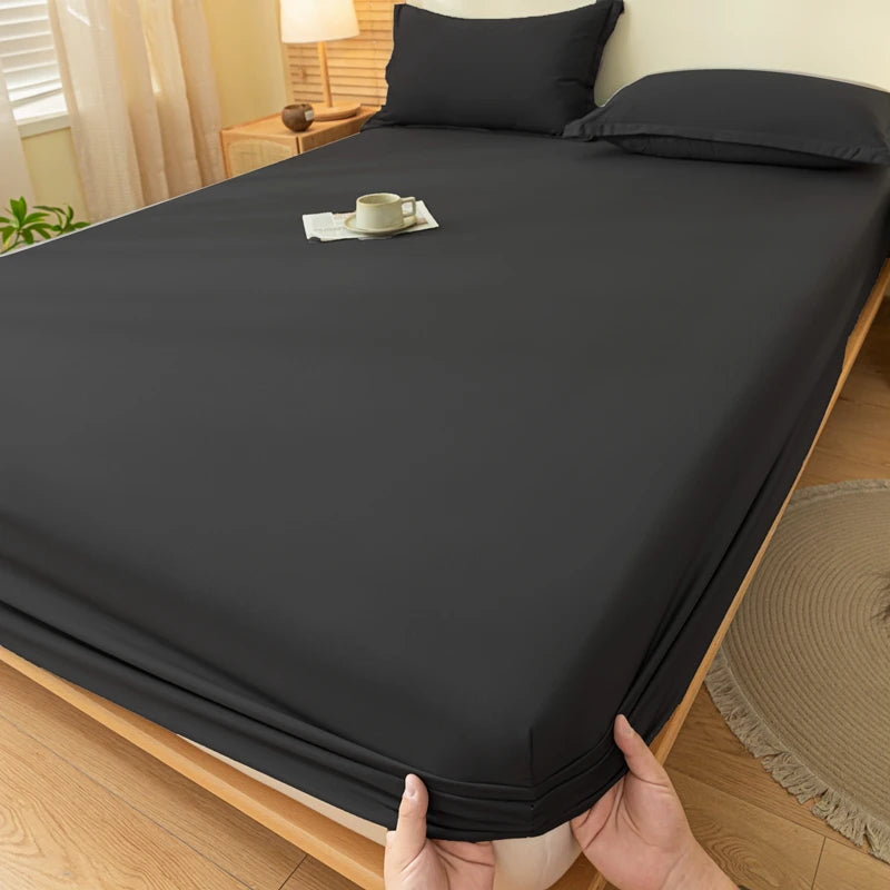 A dark gray fitted sheet is laid out on a bed, showing its smooth texture and elastic edge.