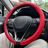 A close-up view of a red steering wheel cover on a black steering wheel inside a car.