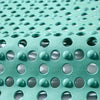 Close-up view of a teal anti-slip shower mat featuring textured surface and various sized drainage holes.
