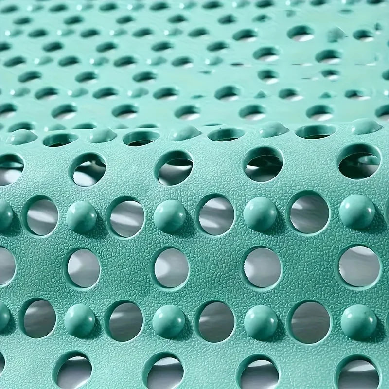 Close-up view of a teal anti-slip shower mat featuring textured surface and various sized drainage holes.