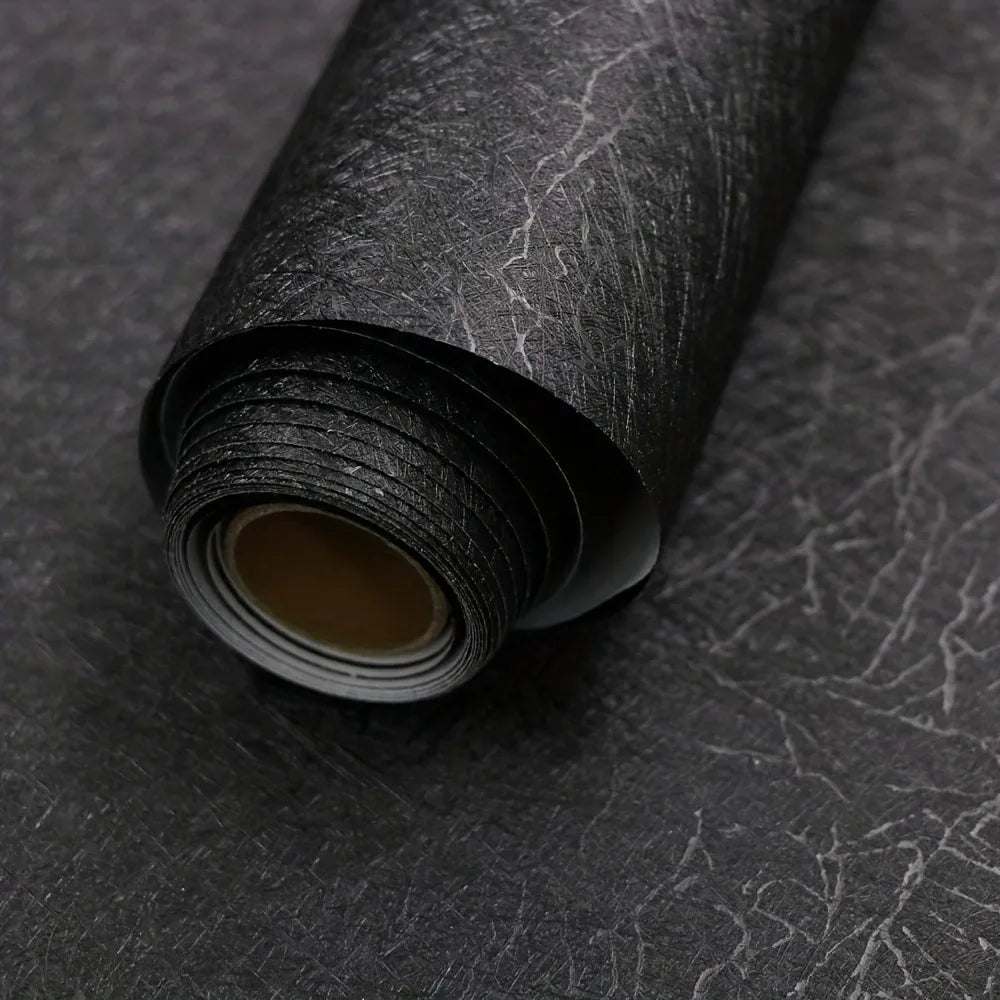 Roll of black self-adhesive wallpaper with a beige backing visible at the end
