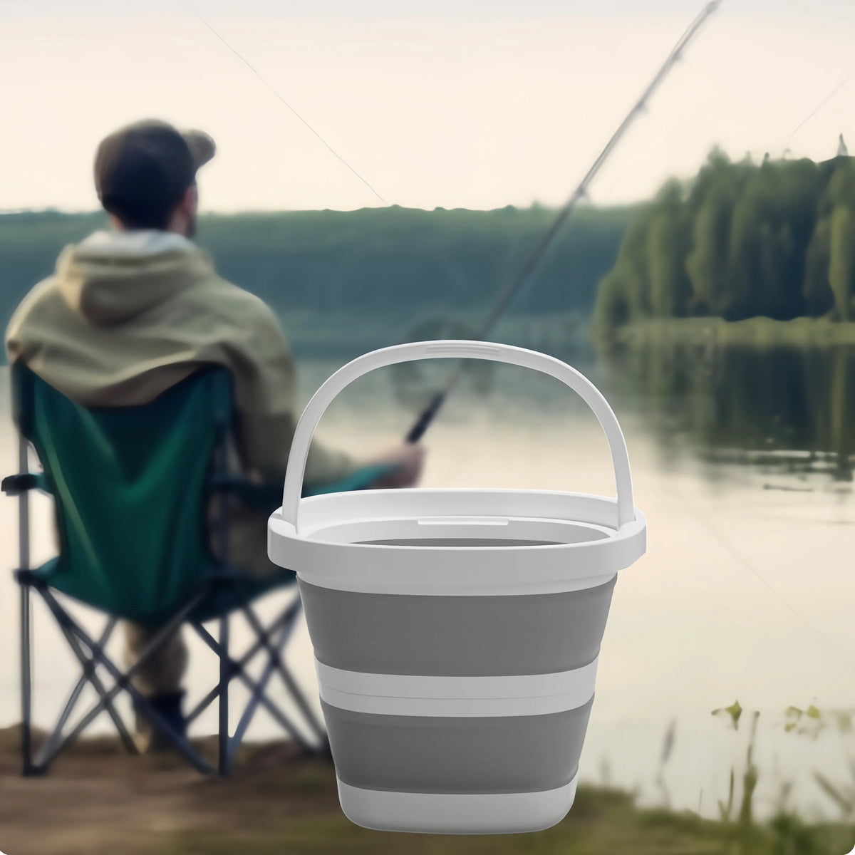 A person is fishing with a collapsible outdoor bucket and carry handle by a body of water.