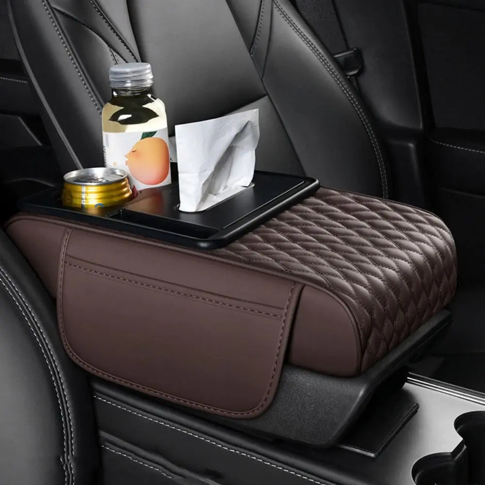 A dark brown quilted car armrest cushion with storage and cup holders is placed on a black car seat.