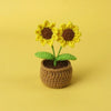 Handcrafted crochet sunflower with yellow petals and brown center growing in a textured green pot