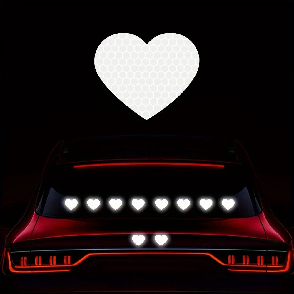 A close-up view of a red car with reflective heart stickers on the rear, set against a black background.