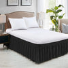 White bedding set featuring a black elastic wrap-around bed skirt with ruffles on a bed.