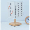 A white ceramic table lamp with a textured linen shade featuring black calligraphy characters on the side.