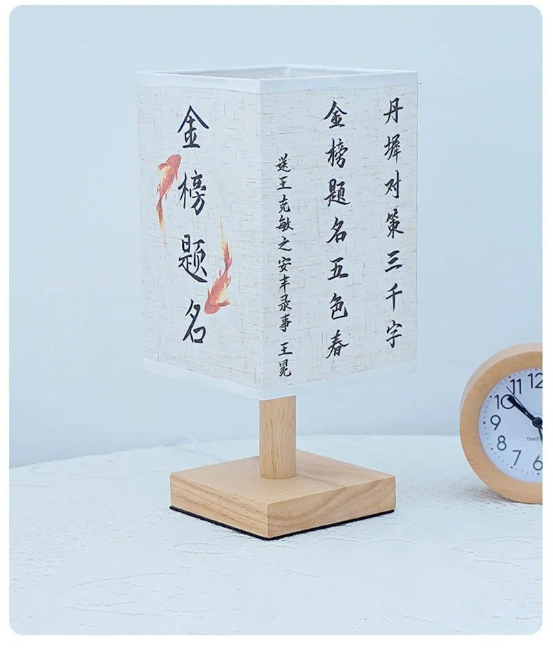 A white ceramic table lamp with a textured linen shade featuring black calligraphy characters on the side.