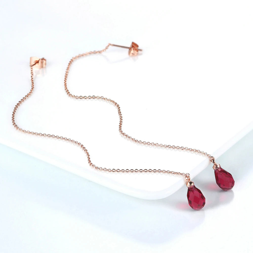 Collar de cadena dorado con un pequeño pendiente y un pendiente de rubí en forma de lágrima.